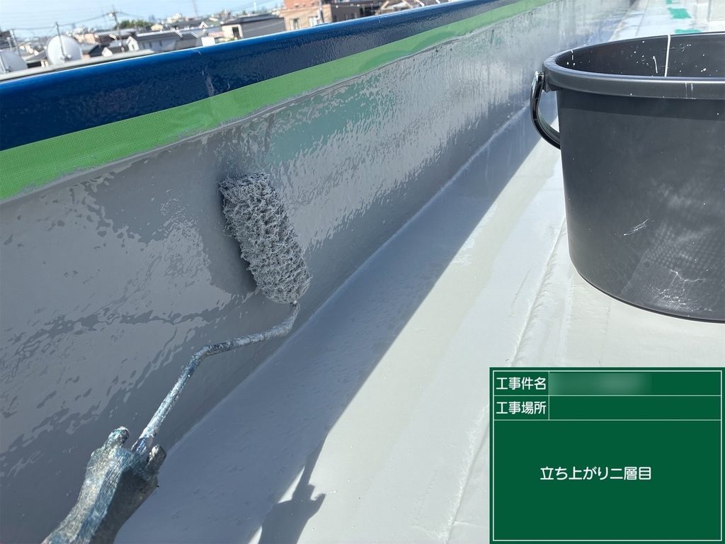 屋上の立ち上がり部分に防水材を塗り重ねる様子