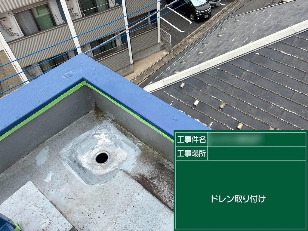 屋上の排水口に改修用ドレンを設置する様子